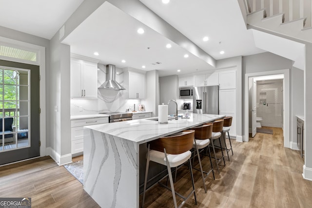 1010F Tailwater, Greensboro, GA 30642 - kitchen featuring a large island, appliances with stainless steel finishes, a sink, white cabinets, and wall chimney exhaust hood