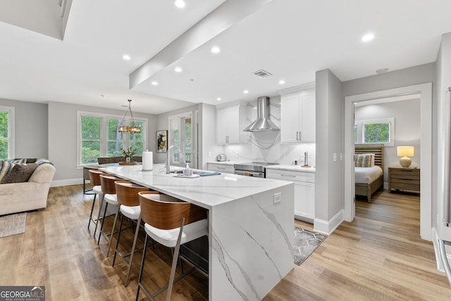 1010F Tailwater, Greensboro, GA 30642 - kitchen with white cabinets, a sink, visible vents, wall chimney exhaust hood, and a spacious island