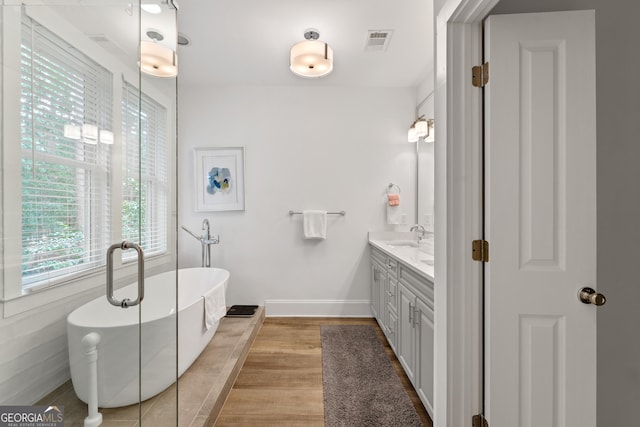 1010F Tailwater, Greensboro, GA 30642 - bathroom featuring visible vents, vanity, wood finished floors, baseboards, and a soaking tub