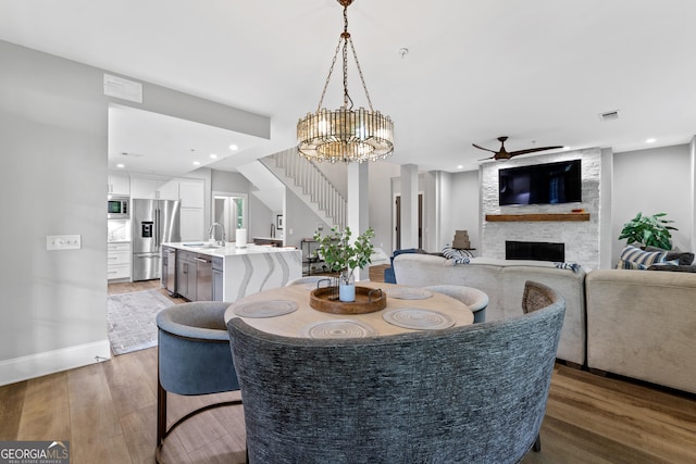 1010F Tailwater, Greensboro, GA 30642 - dining space featuring visible vents, ceiling fan with notable chandelier, wood finished floors, and a large fireplace
