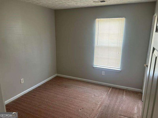 empty room with baseboards, a textured ceiling, carpet flooring, and plenty of natural light