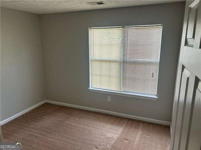 spare room with carpet, baseboards, plenty of natural light, and visible vents