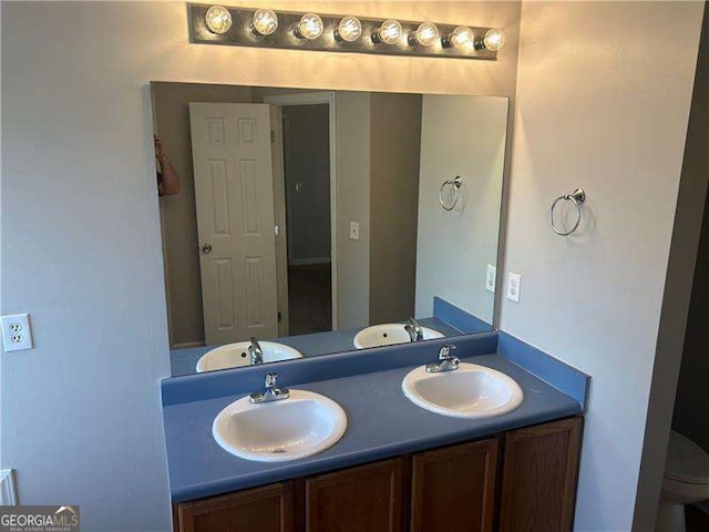 bathroom with a sink, double vanity, and toilet