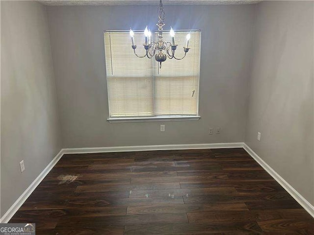unfurnished dining area featuring an inviting chandelier, dark wood-style flooring, and baseboards