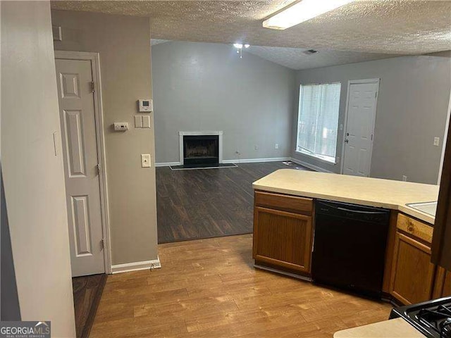 kitchen with a textured ceiling, baseboards, black dishwasher, light wood finished floors, and light countertops