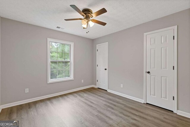 470 Brackin Trce, Grayson, GA 30017 - unfurnished bedroom with a textured ceiling, a ceiling fan, baseboards, wood finished floors, and visible vents