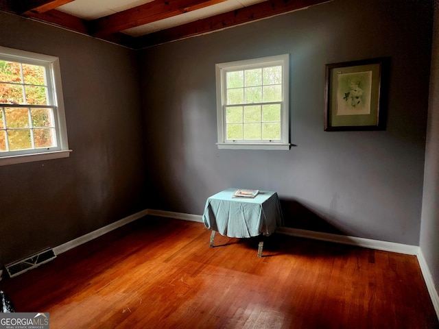 spare room with baseboards, a wealth of natural light, beam ceiling, and visible vents