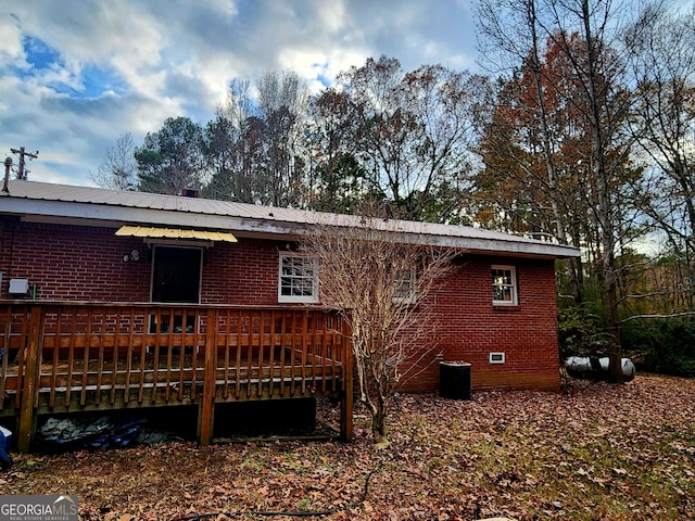 rear view of house featuring brick siding, crawl space, a wooden deck, and metal roof