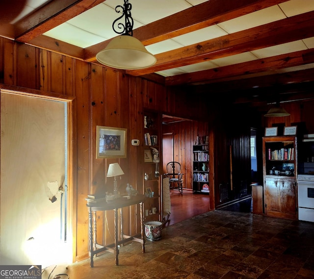 hallway featuring wooden walls, stone finish floor, and beamed ceiling