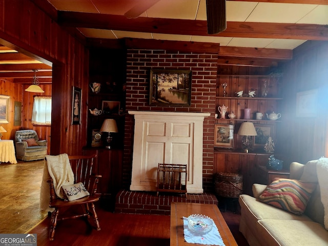 living area with wood finished floors, wood walls, beam ceiling, and a fireplace
