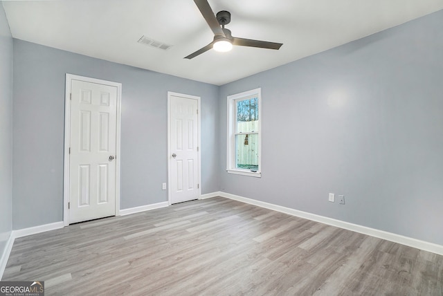 unfurnished bedroom featuring ceiling fan, baseboards, visible vents, and light wood-style flooring
