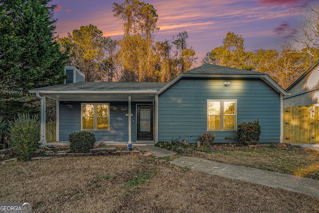 ranch-style house with a porch, a chimney, and a front lawn