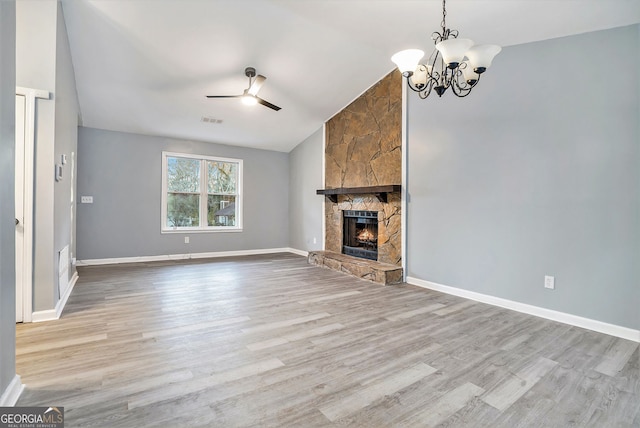 unfurnished living room with vaulted ceiling, ceiling fan with notable chandelier, wood finished floors, and visible vents
