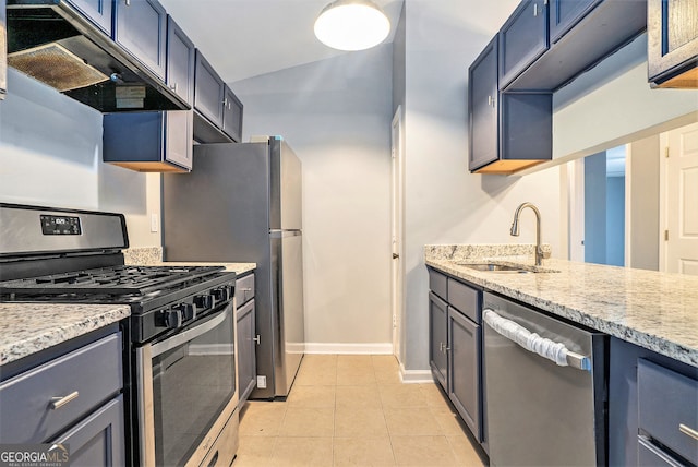 kitchen with light tile patterned flooring, light stone countertops, appliances with stainless steel finishes, a sink, and under cabinet range hood