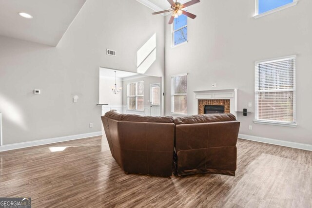 12348 Hillcrest Dr, Hampton, GA 30228 - living area with a glass covered fireplace, baseboards, wood finished floors, a towering ceiling, and visible vents