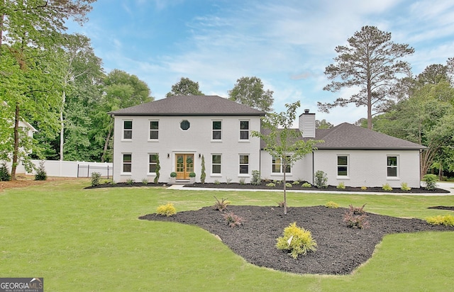 rear view of house featuring a lawn, fence, and a chimney