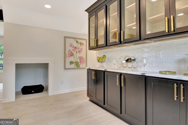 bar featuring bar, backsplash, baseboards, light wood finished floors, and recessed lighting