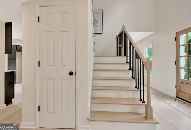 stairway with baseboards, plenty of natural light, and wood finished floors