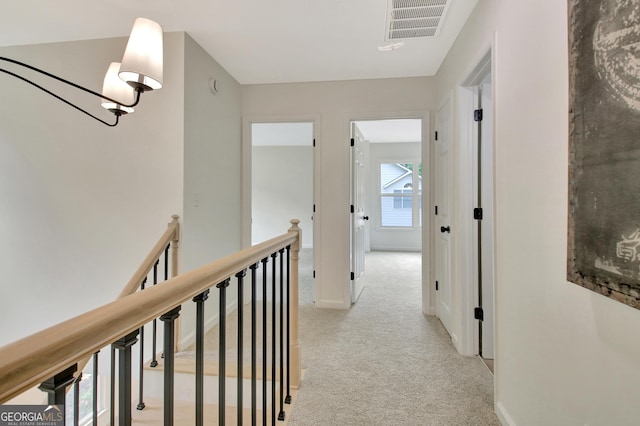 corridor with baseboards, an upstairs landing, light colored carpet, and visible vents