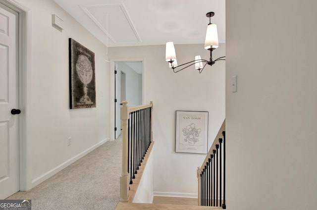 staircase with a notable chandelier, baseboards, carpet, and attic access