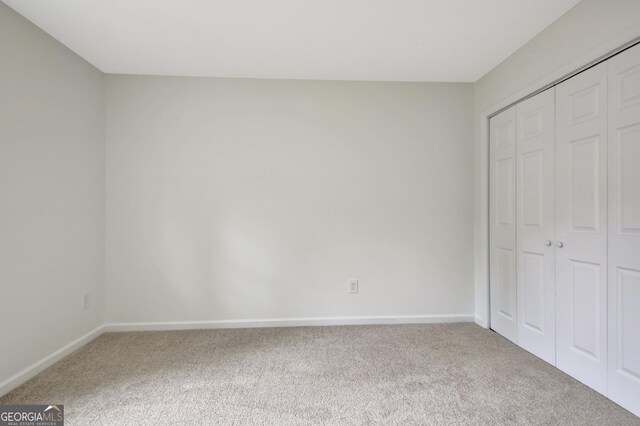 unfurnished bedroom featuring carpet floors, baseboards, and a closet