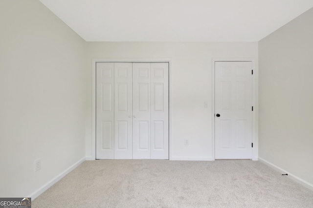 unfurnished bedroom with baseboards, carpet, and a closet