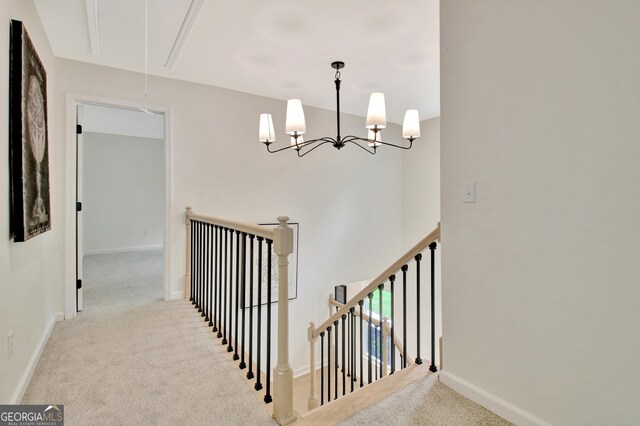 stairway with baseboards, carpet, attic access, and a notable chandelier