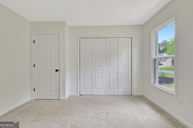 unfurnished bedroom featuring carpet floors, baseboards, and a closet