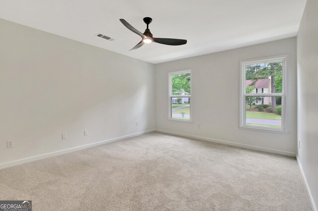 unfurnished room featuring baseboards, light colored carpet, and visible vents