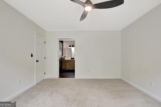 unfurnished bedroom featuring carpet floors, baseboards, ceiling fan, and connected bathroom