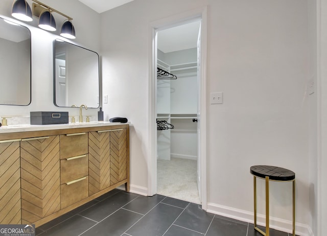 bathroom with double vanity, baseboards, tile patterned flooring, and a walk in closet