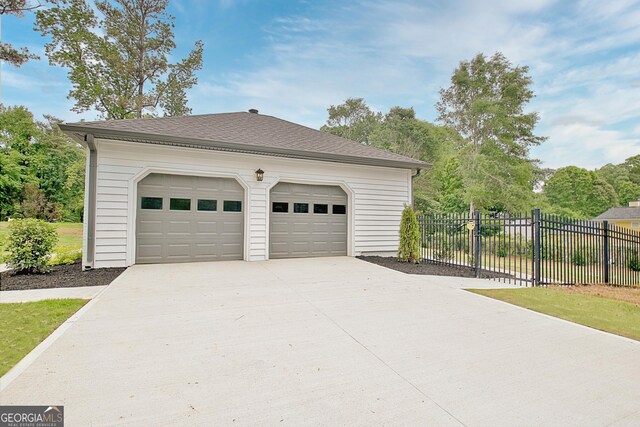garage with concrete driveway and fence