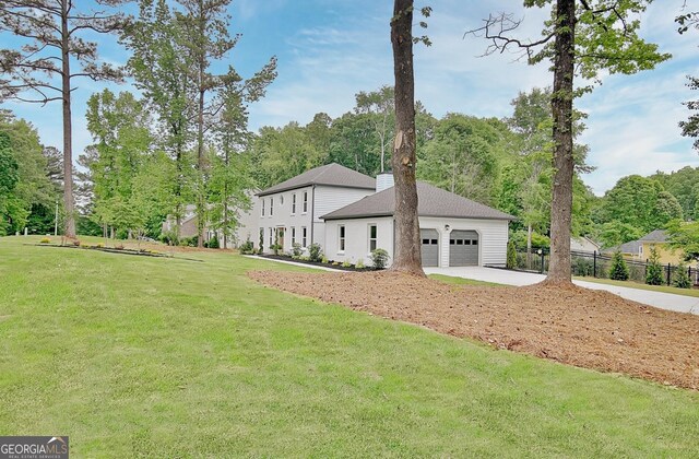 exterior space featuring fence, an attached garage, driveway, and a front lawn