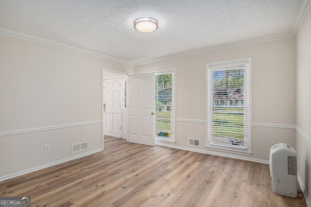 unfurnished room featuring ornamental molding, wood finished floors, and visible vents