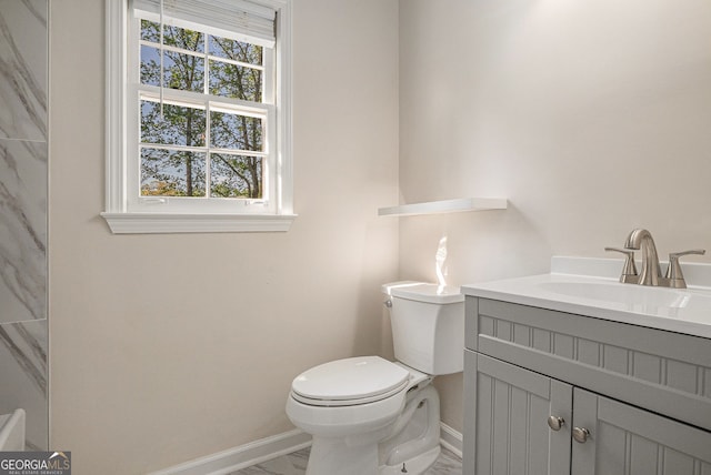 bathroom featuring baseboards, marble finish floor, toilet, and vanity