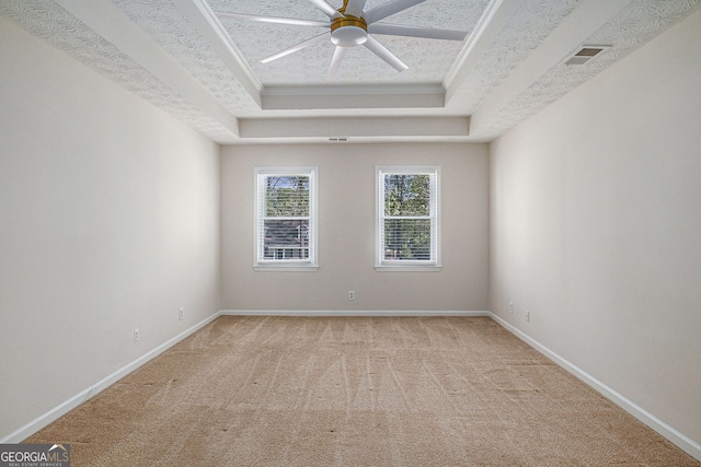 unfurnished room featuring visible vents, baseboards, light colored carpet, a tray ceiling, and a ceiling fan