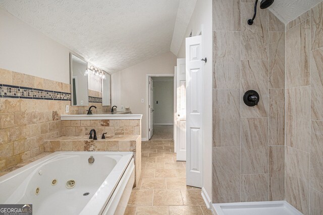 full bathroom featuring a tub with jets, stone finish floor, a textured ceiling, a tile shower, and vaulted ceiling