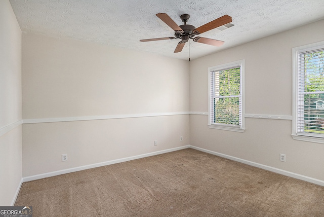 carpeted spare room featuring baseboards, a textured ceiling, and ceiling fan