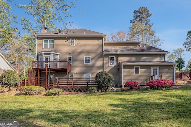 back of house featuring a wooden deck, a yard, and a chimney