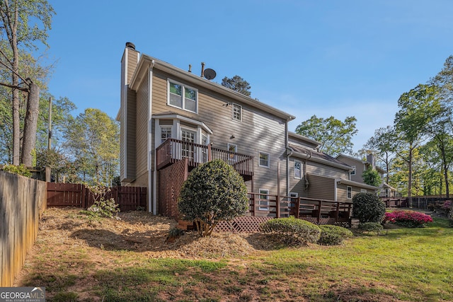 rear view of property with a lawn, fence, a chimney, and a wooden deck