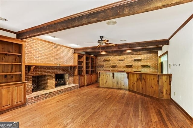 769 Hampton Pl SW, Marietta, GA 30064 - unfurnished living room with beam ceiling, a fireplace, wood-type flooring, brick wall, and a ceiling fan