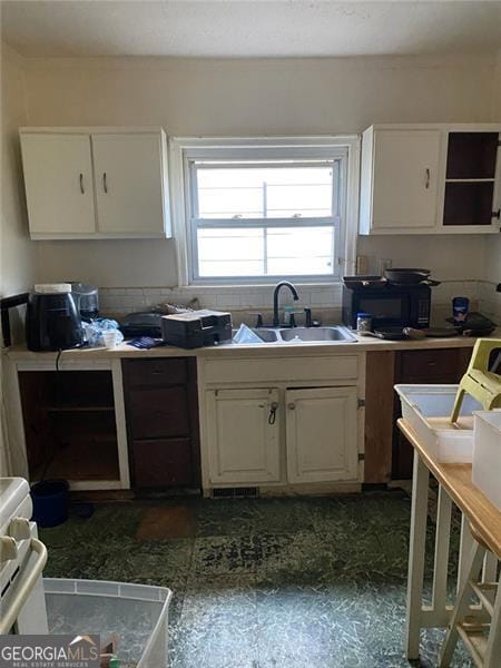 2689 Knox St, Atlanta, GA 30317 - kitchen featuring white cabinets, dark floors, black microwave, and a sink