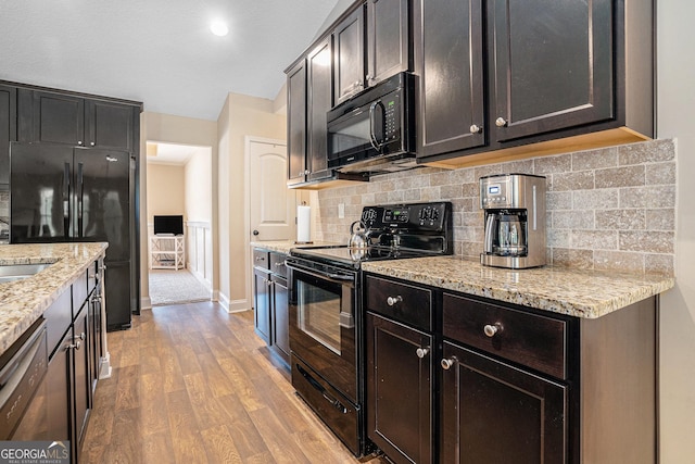kitchen with light stone counters, light wood-style flooring, baseboards, backsplash, and black appliances