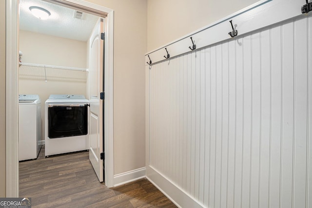 clothes washing area with laundry area, visible vents, baseboards, dark wood finished floors, and independent washer and dryer
