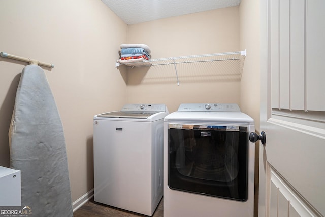 clothes washing area featuring baseboards, laundry area, washing machine and dryer, and wood finished floors
