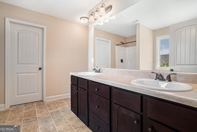 full bathroom featuring double vanity, baseboards, walk in shower, and a sink