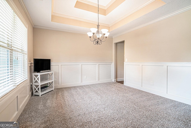 spare room with a raised ceiling, a decorative wall, carpet floors, and a notable chandelier