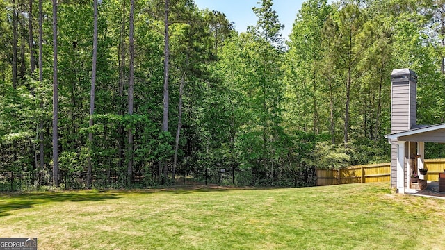 view of yard with a fenced backyard and a view of trees
