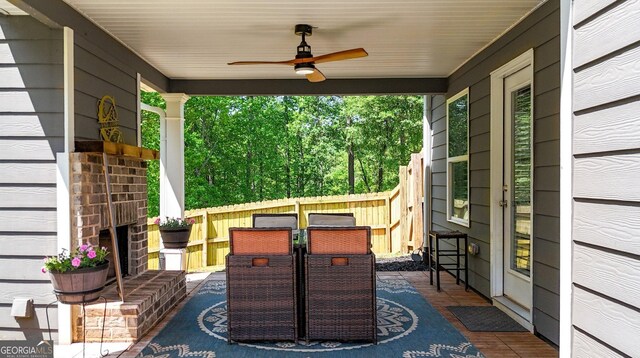 view of patio featuring a porch, ceiling fan, fence, and outdoor dining space