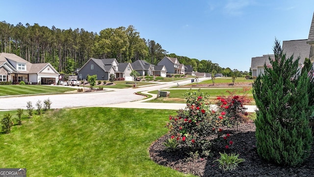 view of property's community with a lawn, an attached garage, driveway, and a residential view